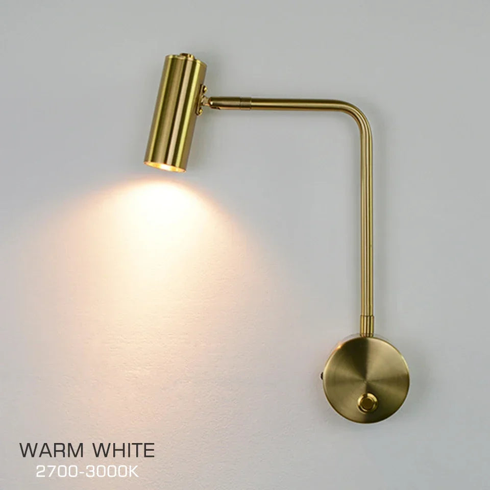 Gold reading wall light by a bed